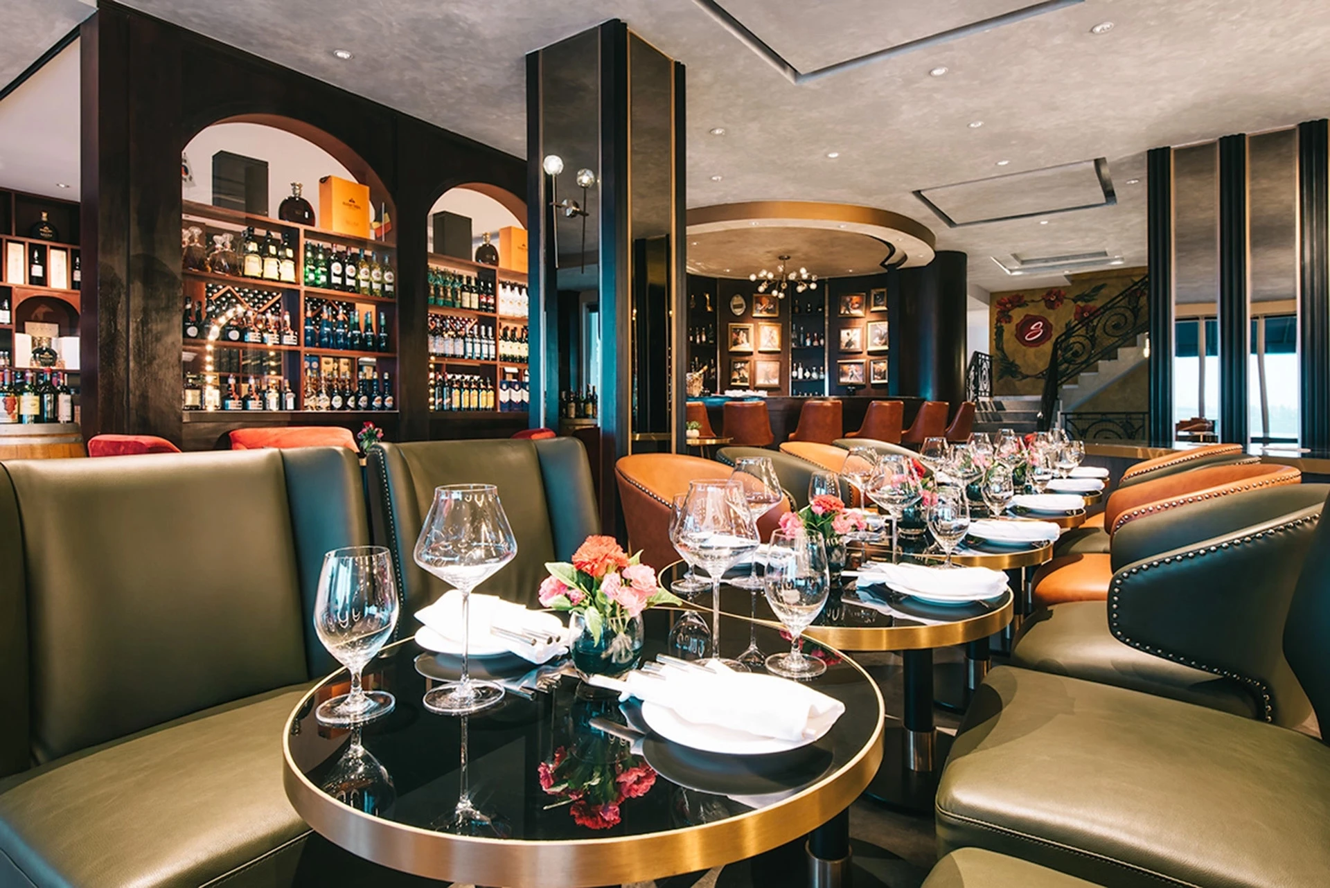 Upscale hotel restaurant with arranged tableware and well-lit bar in the background.