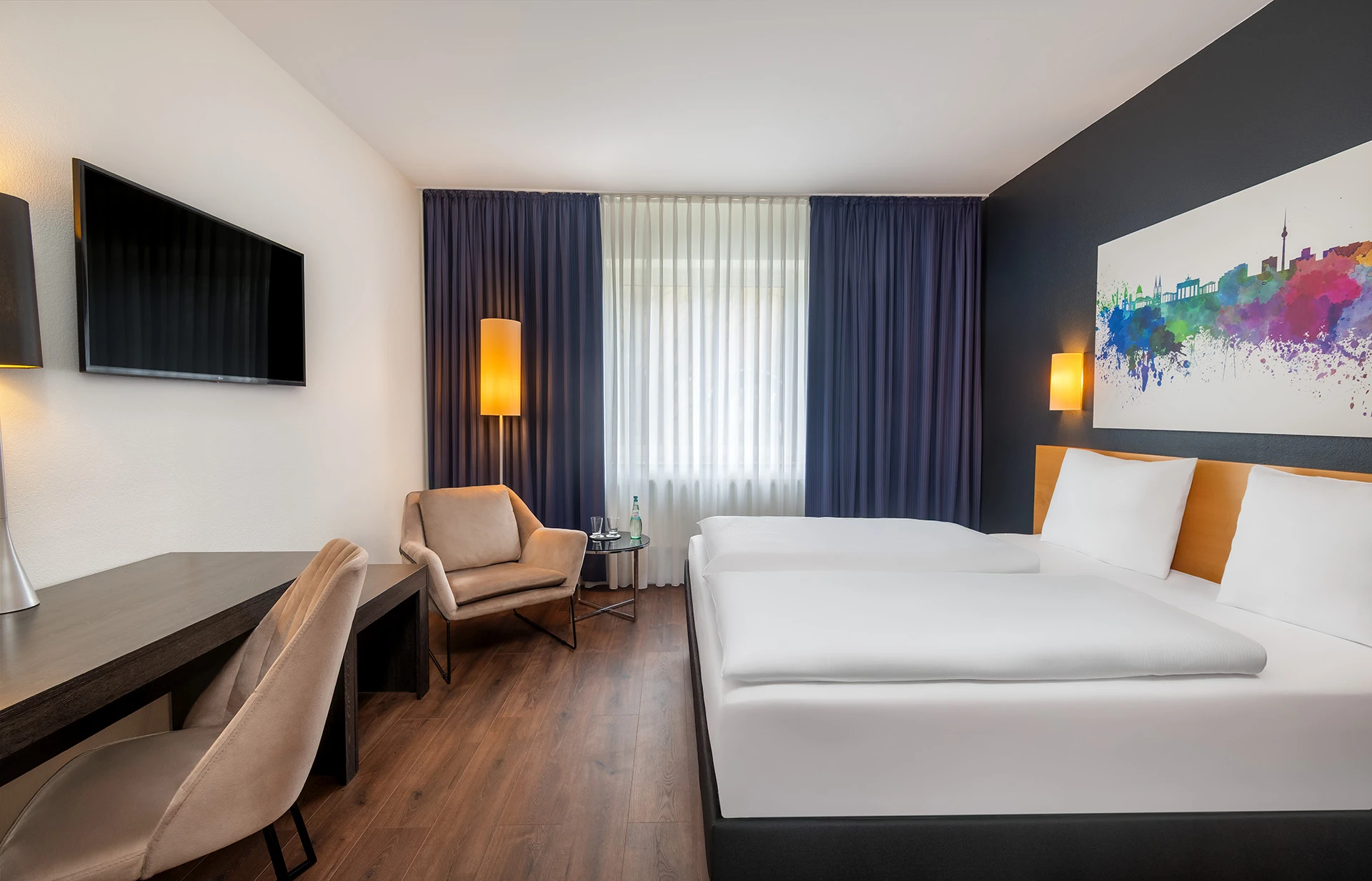 Modern hotel room with twin beds, stylish seating, and simple design elements.