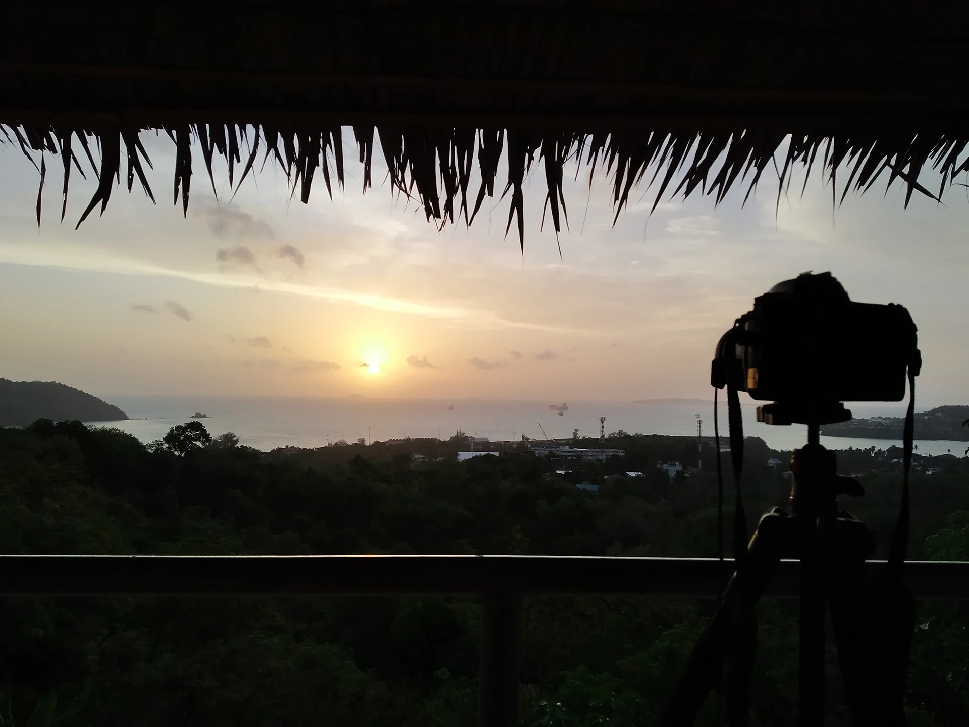 Silhouette of a camera overlooking a sunset coastal landscape