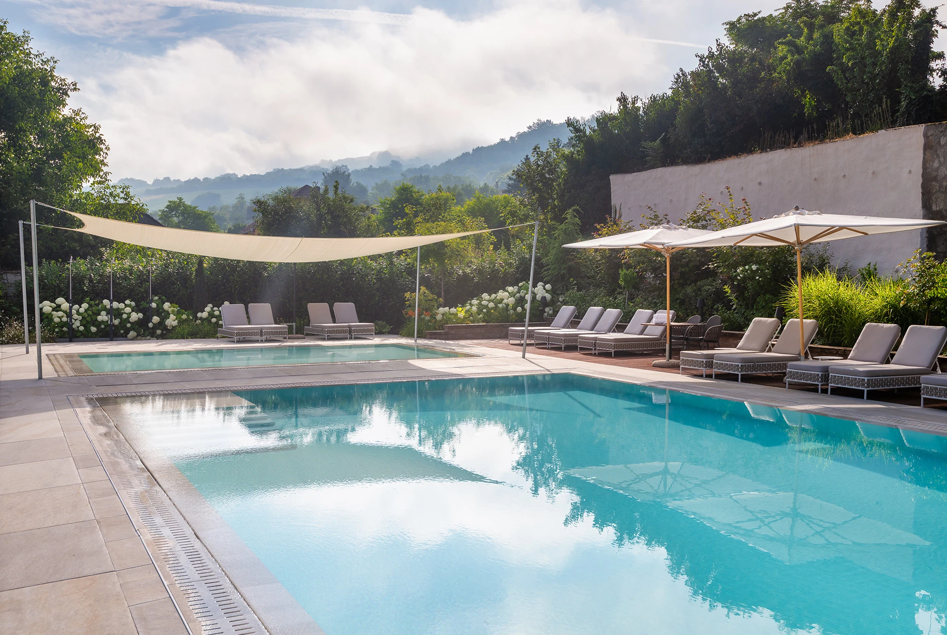 Outdoor pool with sun loungers and mountain views