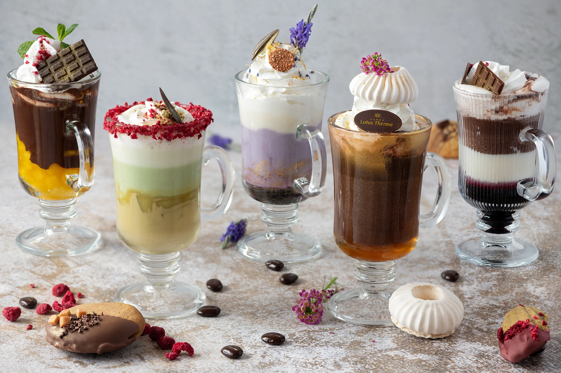 Colorful layered drinks and coffee with whipped cream and decorative toppings