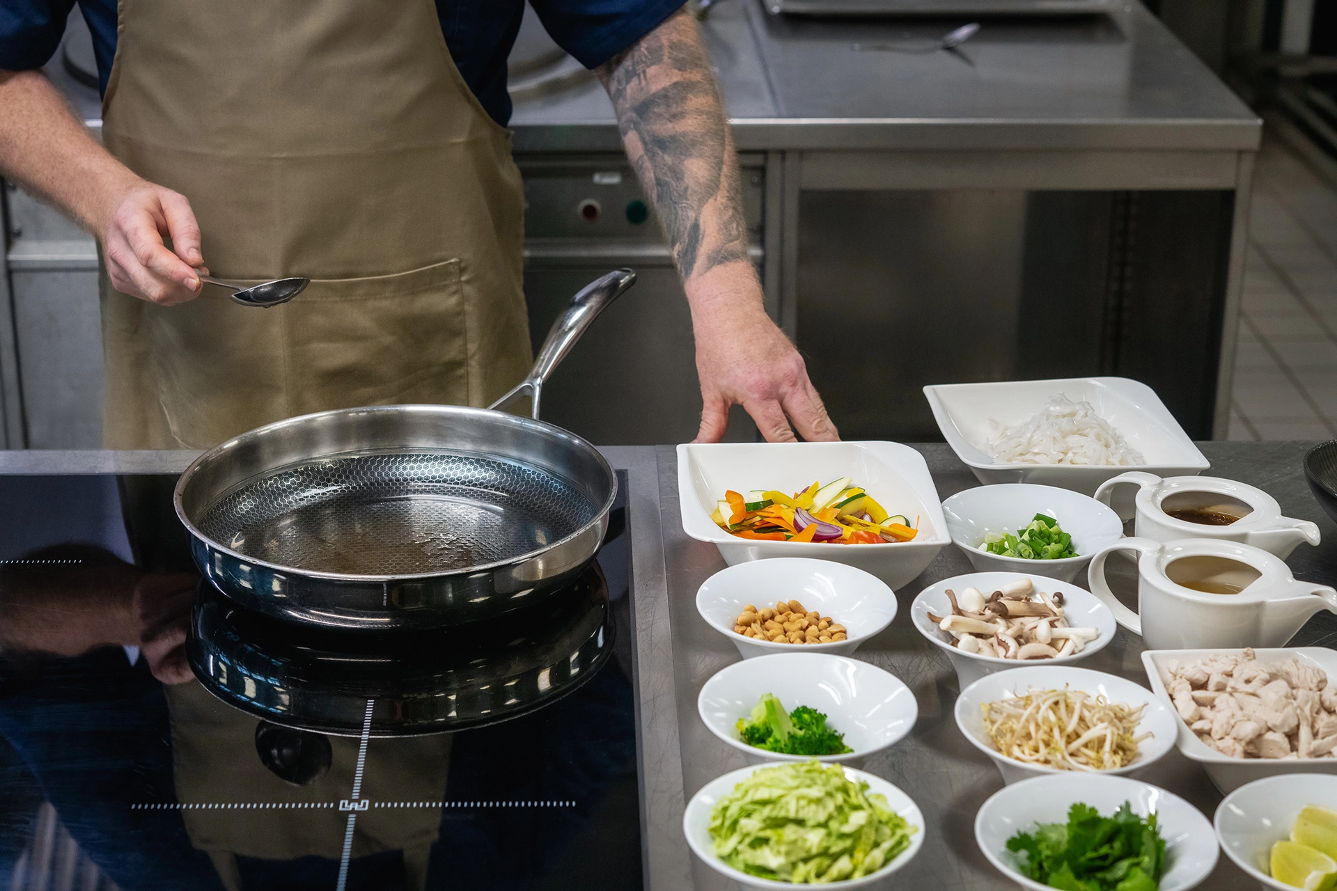 Chef arranging ingredients next to cooking pan in modern kitchen