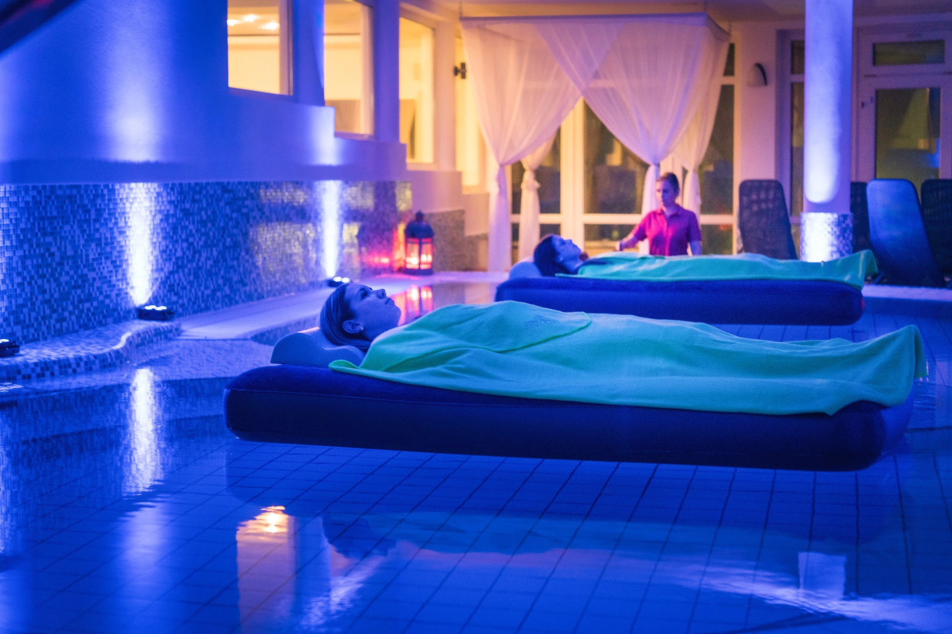 Spa pool at night with blue lighting and floating guests