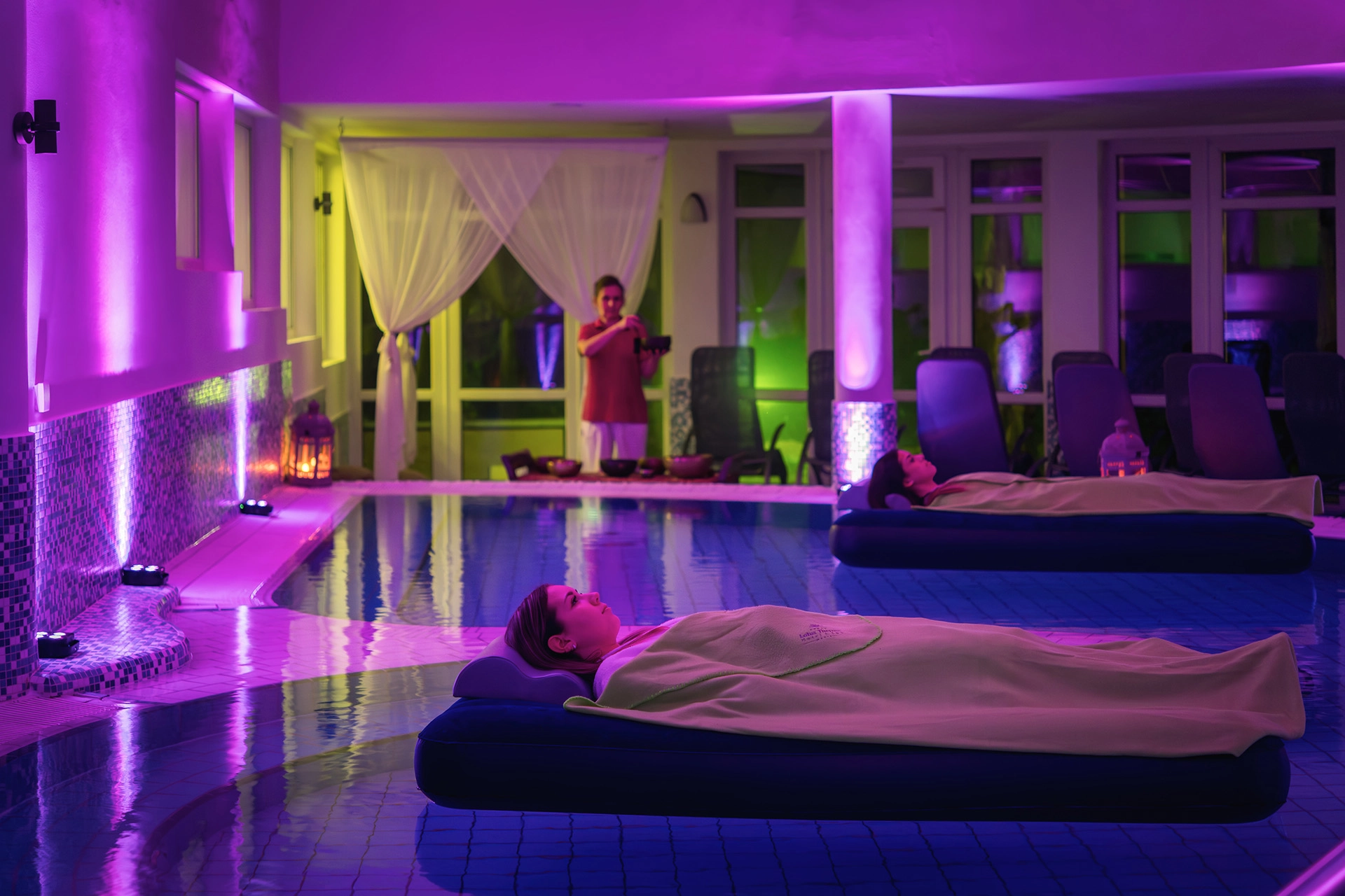 Floating wellness therapy in spa pool with colorful ambient lighting at night