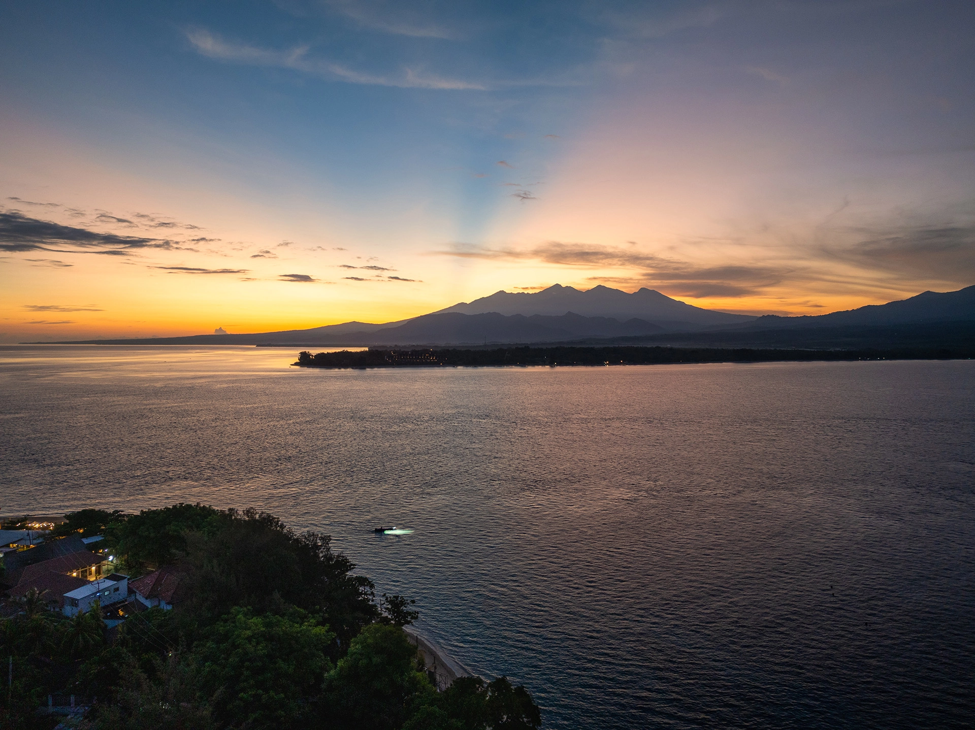 Traditional Indonesian outrigger boat resting on the shore with Mount Agung in the background.
