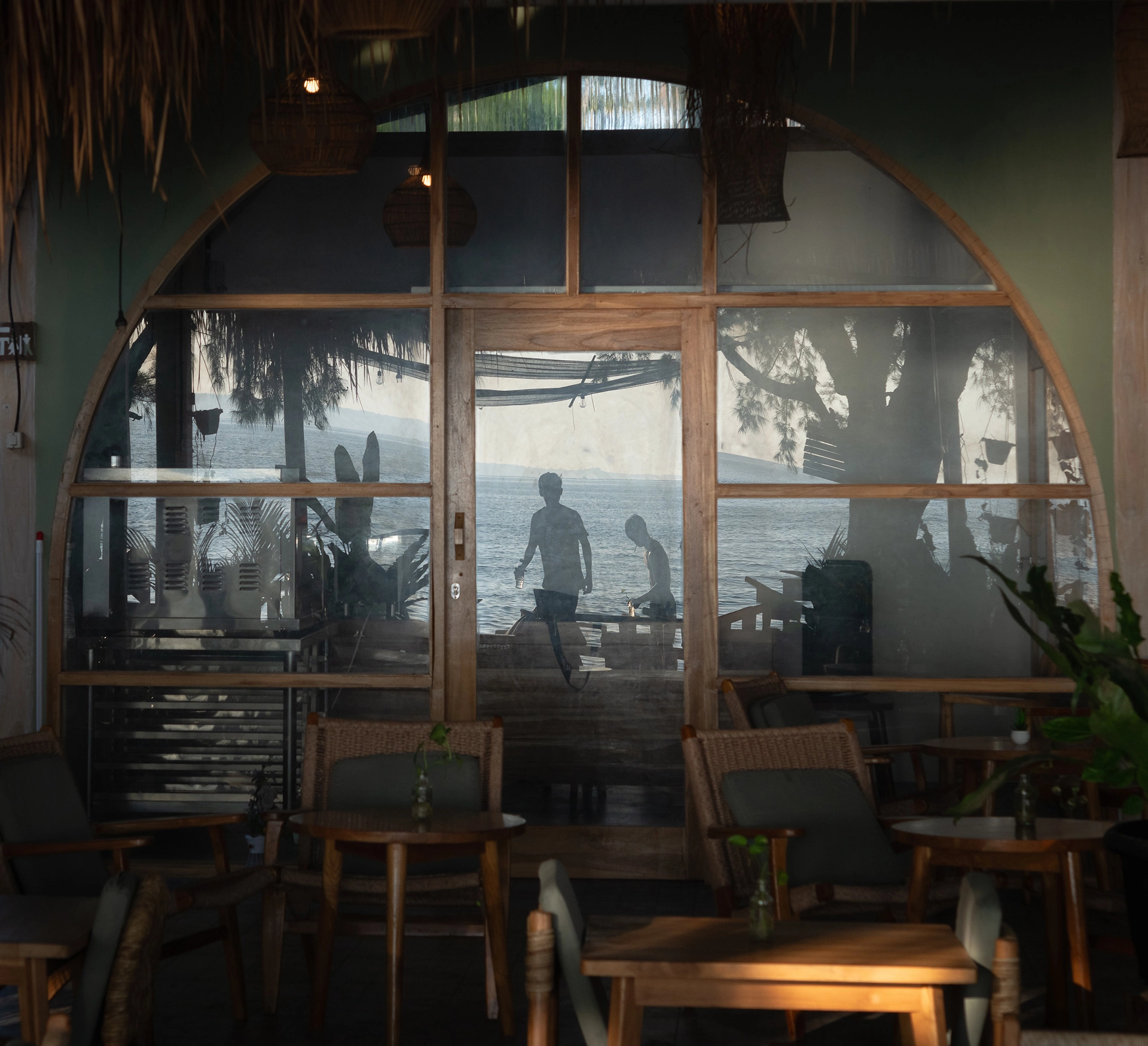Interior of a beachfront café with reflections of the ocean and people enjoying the seaside atmosphere.