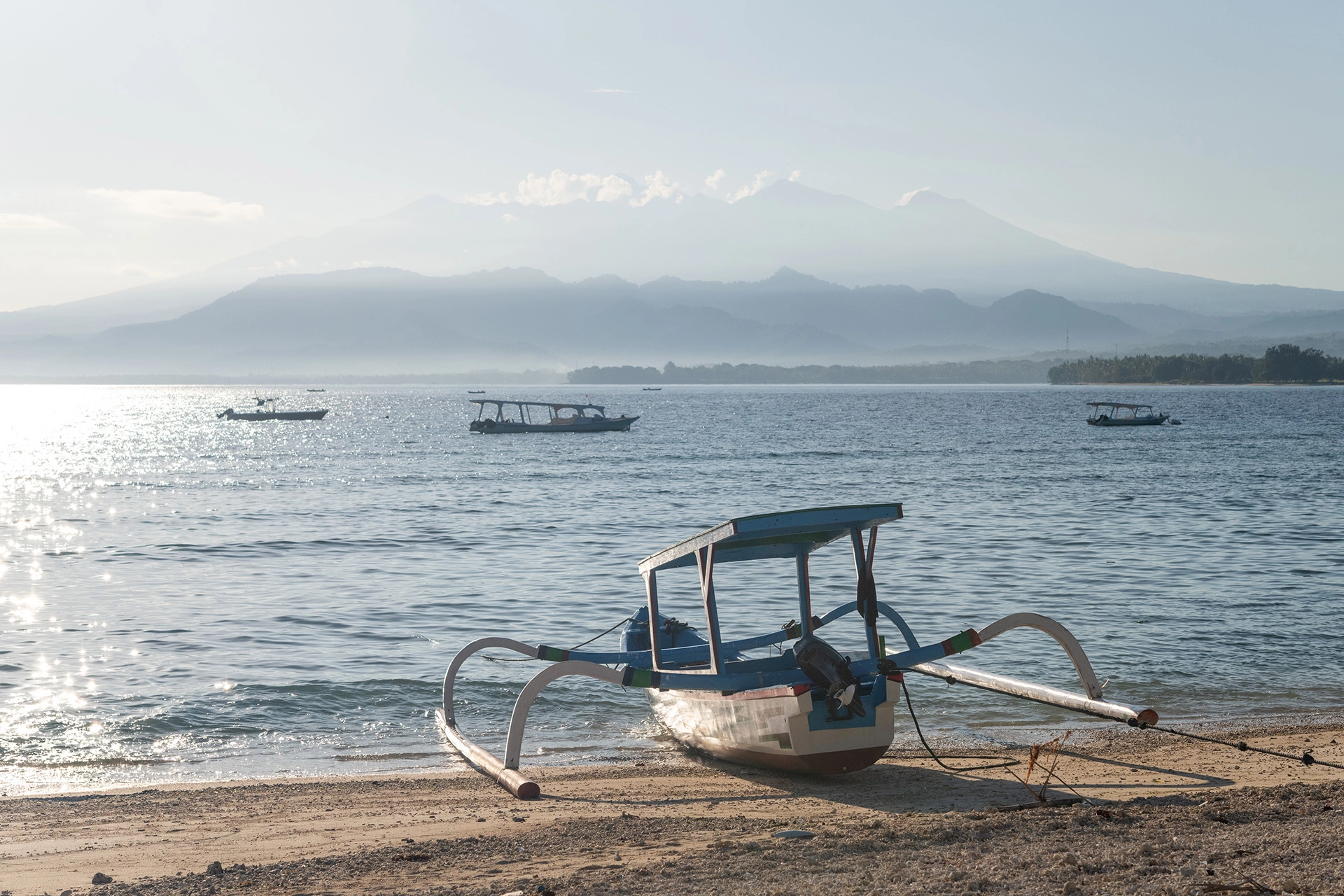 Golden sunset over the sea with the silhouette of Mount Agung beyond the Gili Islands.